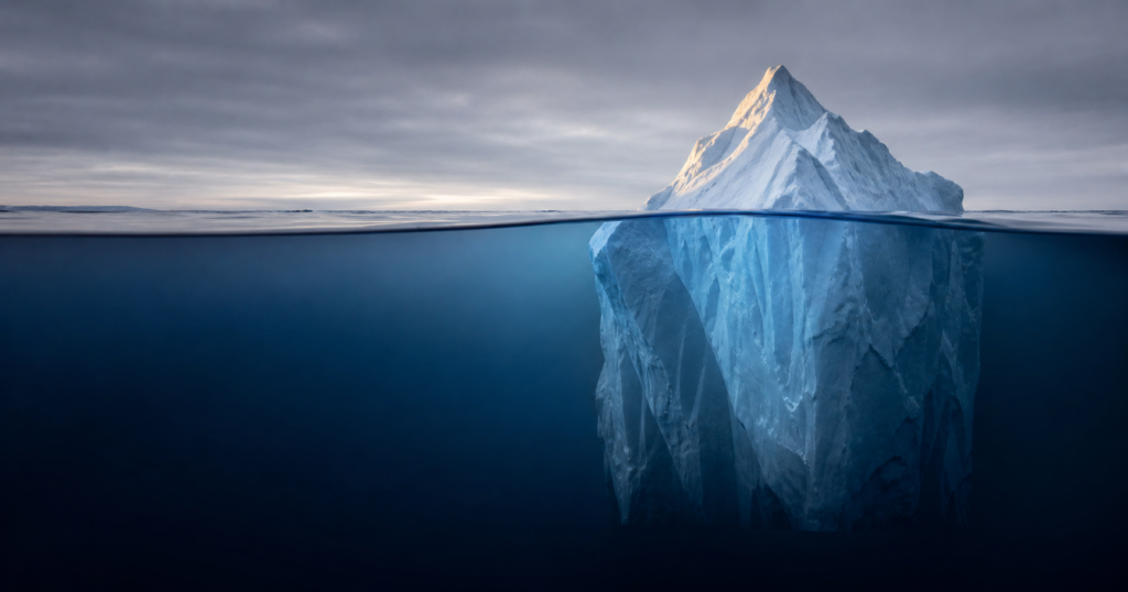 Iceberg above and below water — the iceberg metaphor for Total Cost of Risk in commercial insurance: premium is the visible tip while retained losses, risk control, and administration are the larger mass underwater.